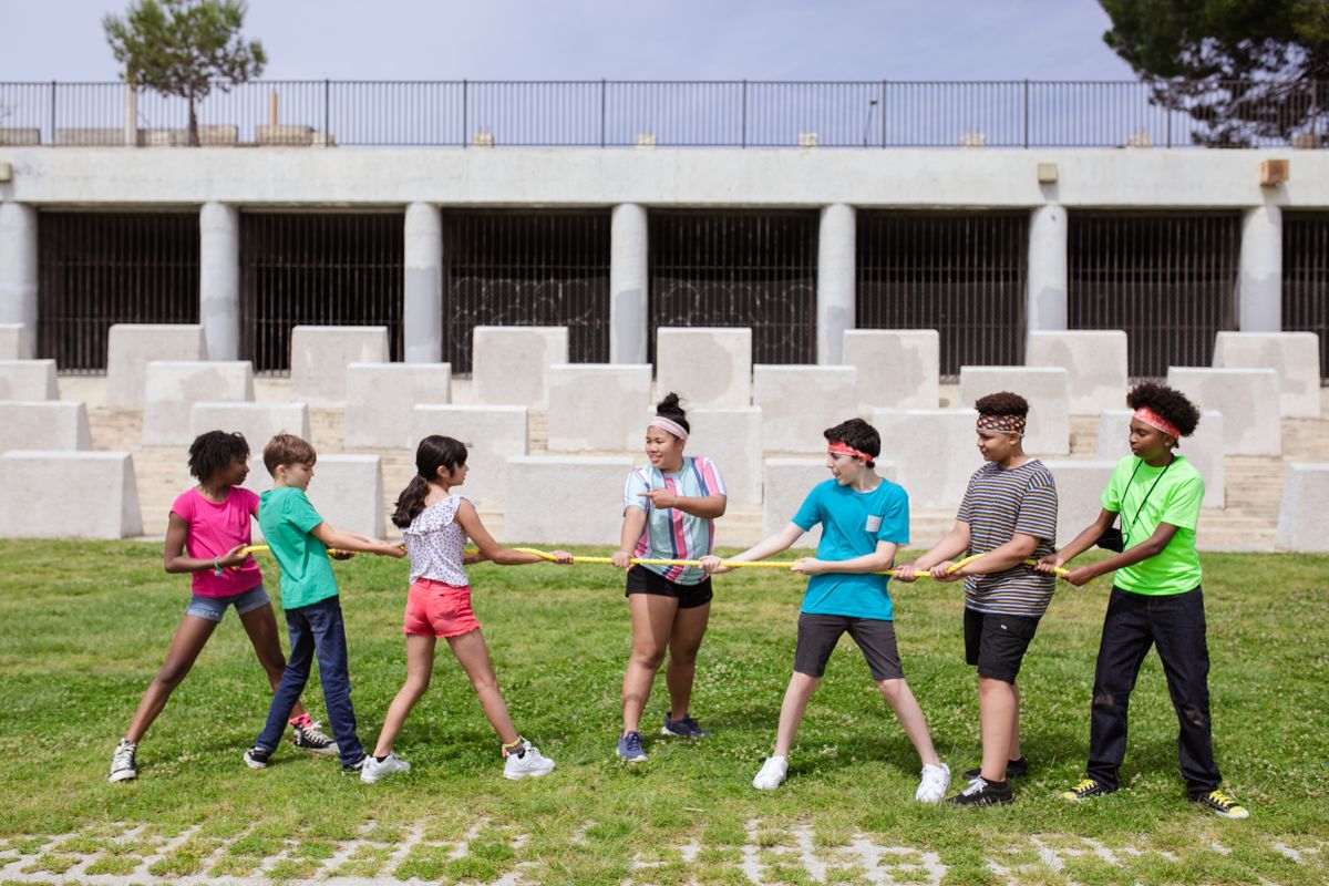 Campers playing tug of war outdoors at summer camp